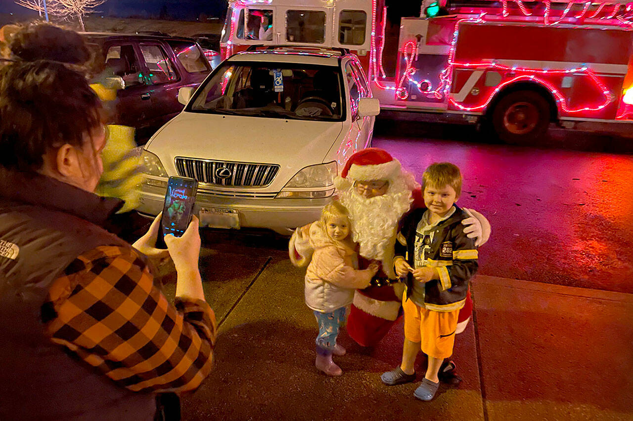 Sequim Gazette photo by Matthew Nash/ Winter, 3, and Gunner, 5, Samples of Sequim pose for a photo with Santa Claus on Dec. 6 during Santa’s Toy and Food Brigade’s tour across Sequim on Dec. 6.