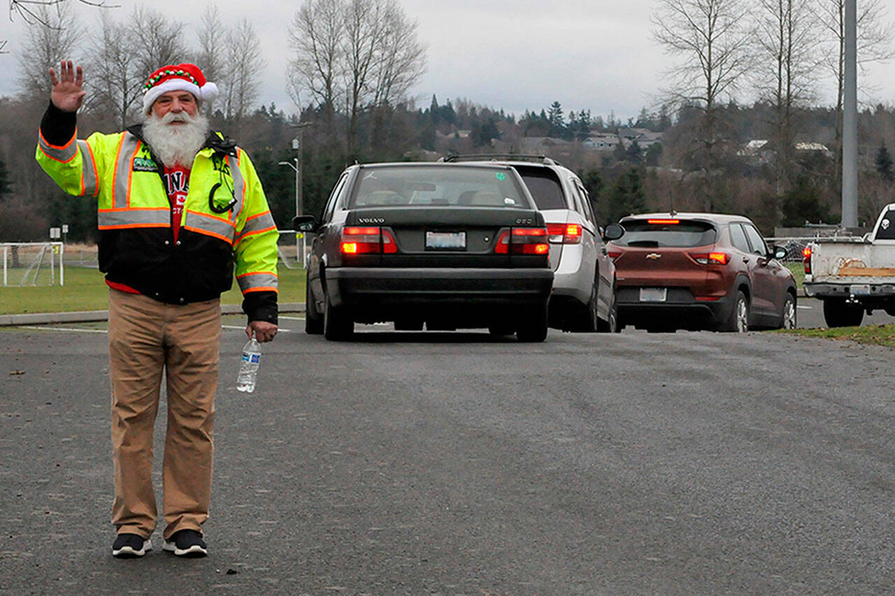 Sequim Gazette photo by Matthew Nash
Butch Zaharias, a captain and division chief with the Community Emergency Response Team (CERT), checks in on drivers and fellow CERT members in festive garb during the Family Holiday Meal Bag distribution event on Dec. 15 in Carrie Blake Community Park.