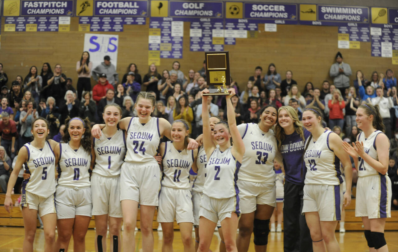 Sequim Gazette photo by Michael Dashiell / The Sequim girls basketball team in February celebrates its first undisputed Olympic League championship since 1987; they finished 14-0 in league. Pictured, from left, are Kaitlyn Bloomenrader, Mikki Green, Taylor Hetying, Dani Herman, Taryn Johnson, Bobbi Mixon, Hannah Bates (with trophy), Jelissa Julmist, Jolene Vaara, Sammie Bacon and Libby Turella.