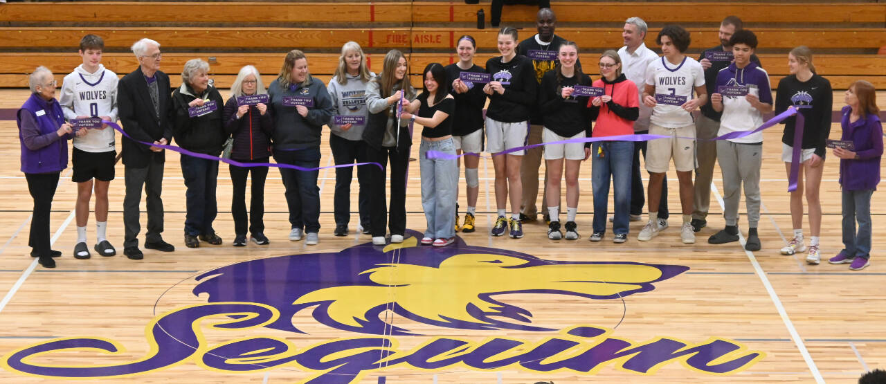 Sequim Gazette photo by Michel Dashiell / Sequim High School athletes, students and coaches, along with representatives from the Sequim-Dungeness Valley Chamber of Commerce, celebrate the school’s newly-refurbished floor inside the Rick Kaps Gymnasium with a ribbon-cutting prior to a basketball doubleheader on Jan. 20. The floor was paid for by voters who approved a four-year, $15 million capital projects levy in February 2021.