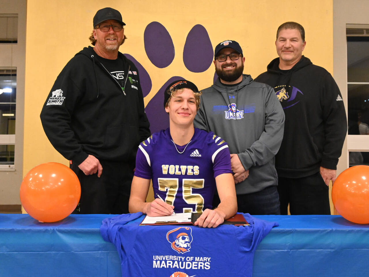 Sequim Gazette photo by Michael Dashiell
Sequim’s Jack Henninger on Feb. 7 signs a letter of intent to play at the University of Mary (North Dakota). The all-Olympic League kicker plans to study occupational therapy and kick for the Marauders’ football squad. Behind him are, from left, soccer coach David Breckenridge, football special teams coach Cody Buckmaster and football head coach Erik Wiker.