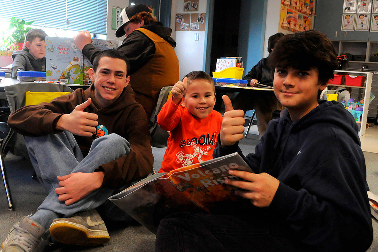 Sequim Gazette photos by Matthew Nash
Sequim Middle School eighth-graders Jude Bower and Ryker Gradillas and Greywolf Elementary kindergartener Brooks Whalen give a thumbs up to a book about volcanoes.