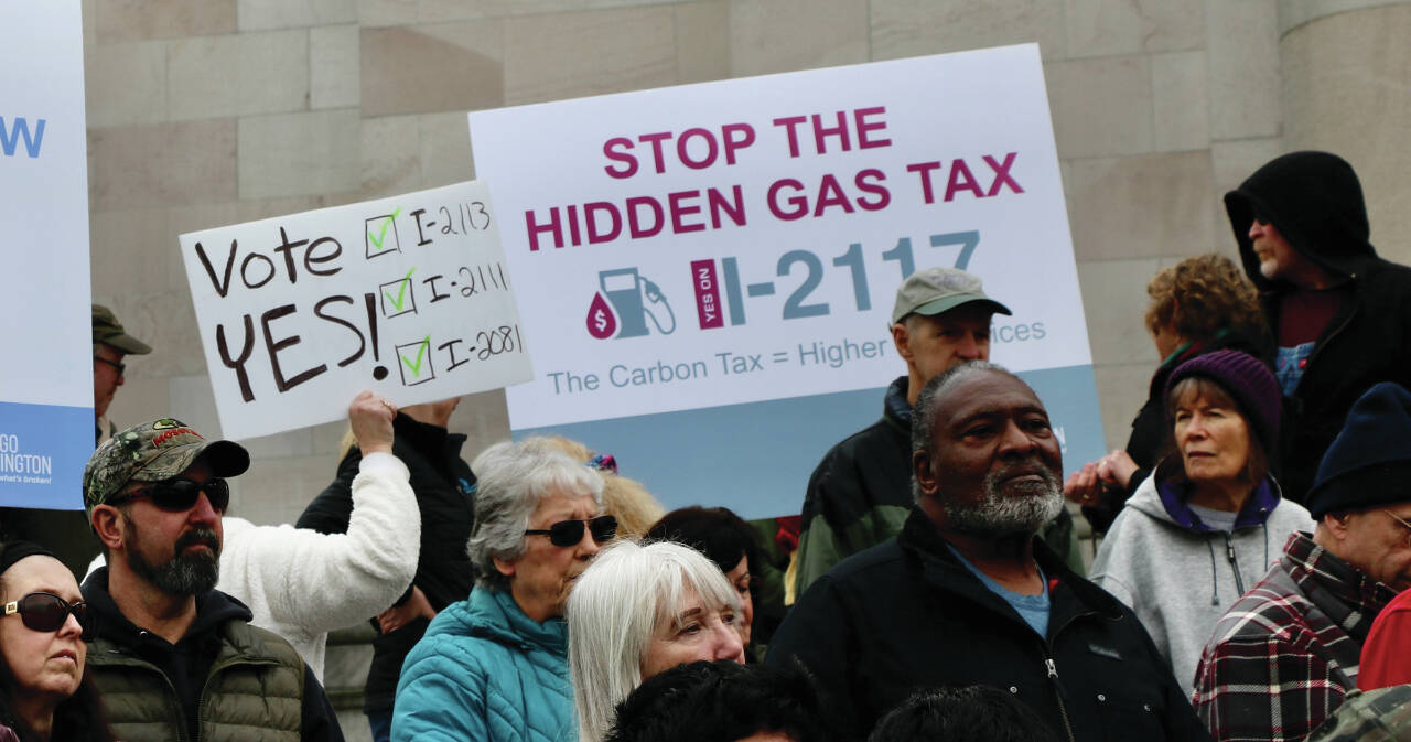 Photo by Aspen Anderson/Washington State Journal / Protestors and signature gatherers on the citizen initiatives gather on the capitol steps, with some holding signs to “Stop the hidden gas tax.”