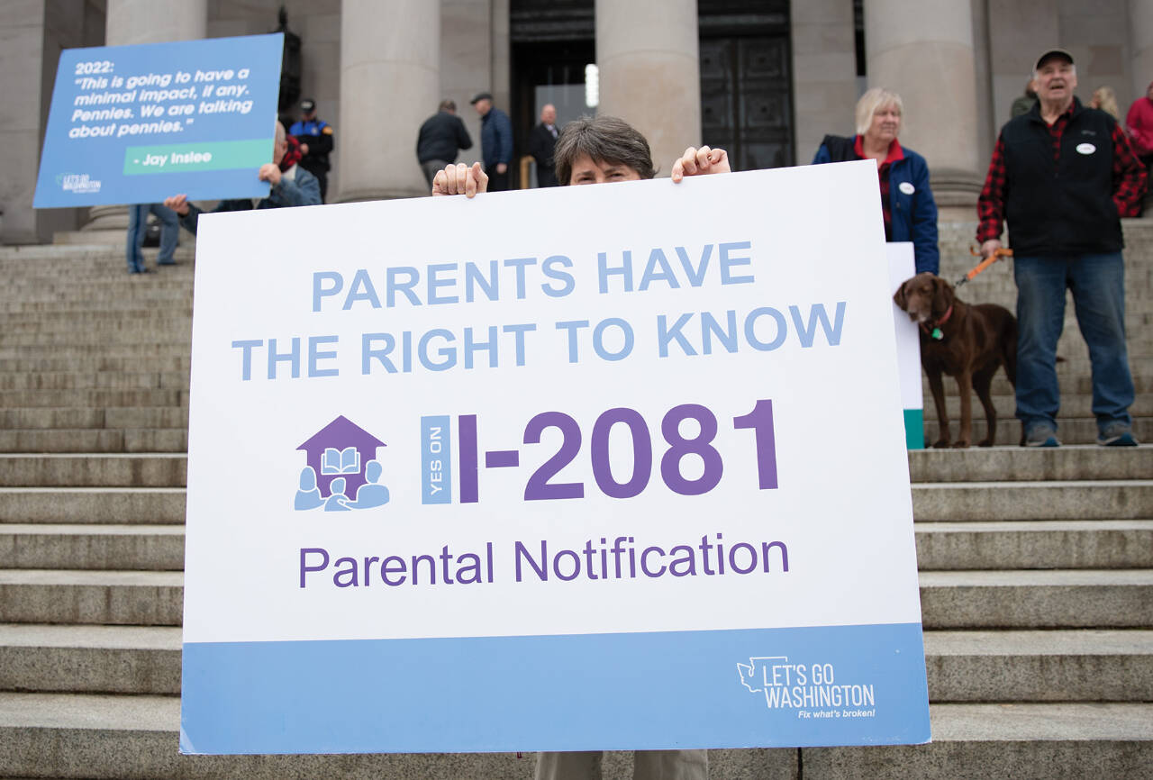 Photo by Mary Murphy/Washington State Journal / A demonstrator carries a sign calling for passage of a parental notification initiative during a protest in Olympia. The initiative was approved by the Legislature.