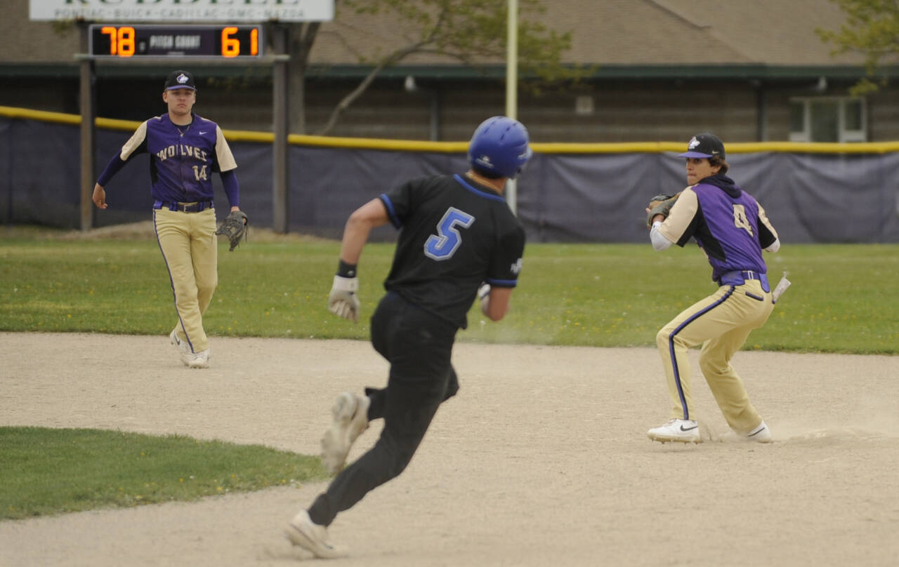 Sequim Gazette photo by Michael Dashiell / With shortstop Devyn Derringer (left) looking on, Sequim second baseman Bryant Laboy turns a double play in the top of the fifth inning as the Wolves host North Mason on April 24.