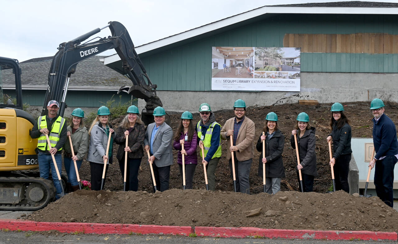 Staff from the North Olympic Library System (NOLS) join project partners at the groundbreaking of the Sequim Library expansion on Wednesday. Pictured, from left, are Kyle and Carrie Priest, owners of Hoch Construction; NOLS board members Jennifer Pelikan; Cyndi Ross and chair Mark Urnes; NOLS collection services manager Erin Shield, facilities manager Brian Phillips, executive director Noah Glaude and Sequim Library manager Emily Sly; Marlo Dowell of Acila Consulting; and Pia Westen and Adam Hutschreider of SHKS Architects. (Michael Dashiell/Olympic Peninsula News Group)