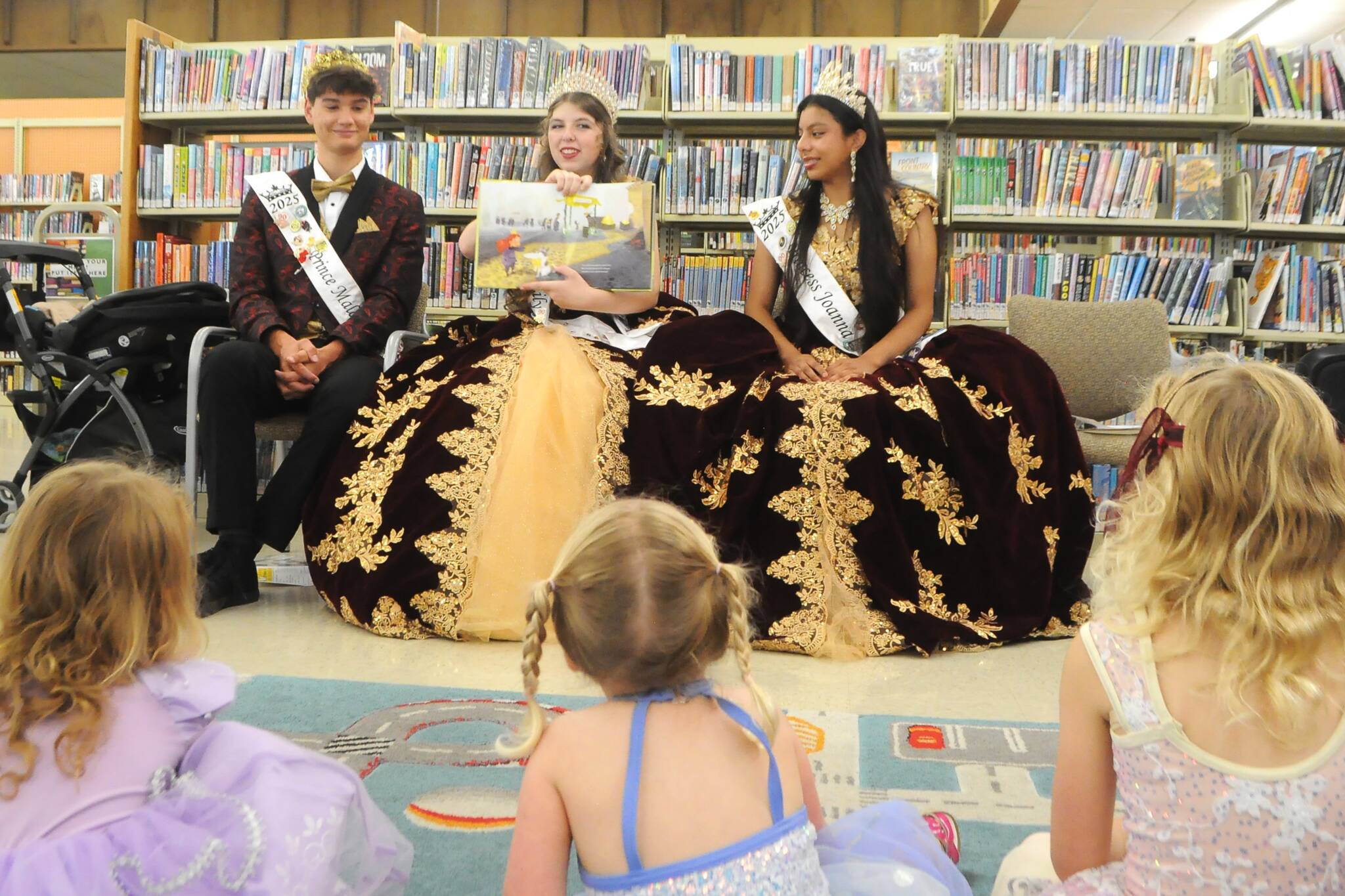 Sequim Gazette photo by Matthew Nash
Sequim Irrigation Festival royalty, from left, Prince Malachi Byrne, Queen Lily Tjemsland, and Princess Joanna Morales read the book “Princess Unlimited” to a crowd of young readers on July 1 at Storytime with the Royal Court at the Sequim Library Temporary Location.