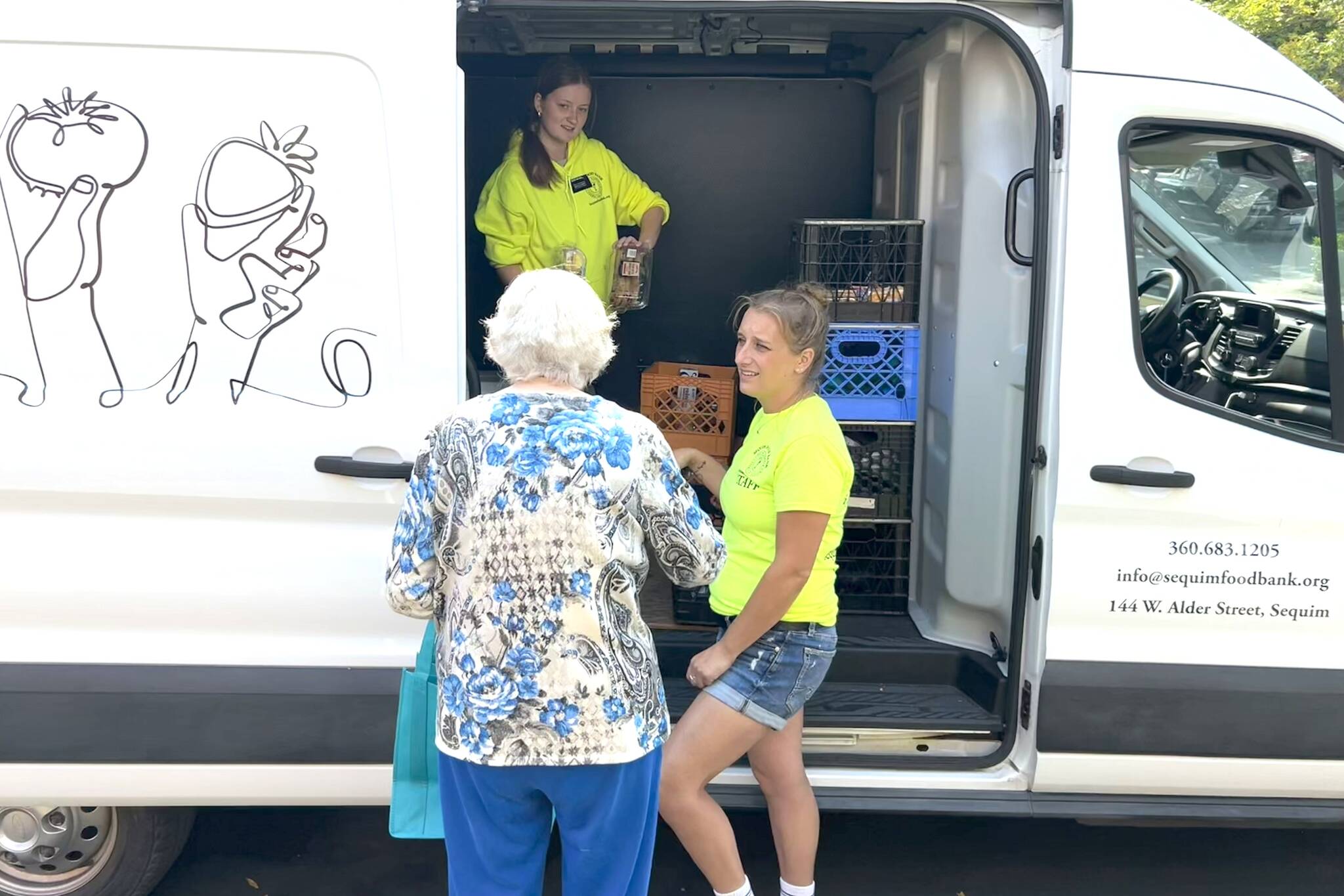Sequim Gazette photo by Matthew Nash/ Emily Callahan, the Sequim Food Bank’s Mobile Food Pantry coordinator, on right, with help from Lili Mitchell, a service missionary with the Church of Jesus Christ of Latter-day Saints, assist a visitor at Suncrest Village, one of the truck’s six stops each week to bring food bank services to locations in the Sequim area.