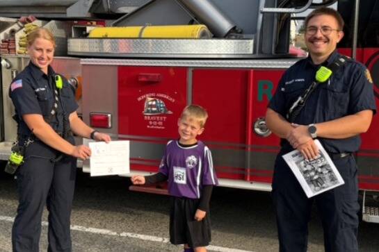 Photo courtesy Clallam County Fire District 3
Through Sept. 30, children ages 3-12 can participate in a contest to highlight Fire Prevention Week (Oct. 5-11). Children ages 3-6 can color a firetruck and older kids can diagram escape routes for their family’s home. Here, Dash Anderson shows off his coloring skills to firefighters Libby Swanberg and Jared Kneidl. Pick up the coloring and diagram sheets at Hi-Way 101 Diner (no purchase necessary), 392 W. Washington St., or at the Sequim Gazette, 175 W. Washington St. The contest is sponsored by the Gazette, Hi-Way 101 Diner and Clallam County Fire District 3.