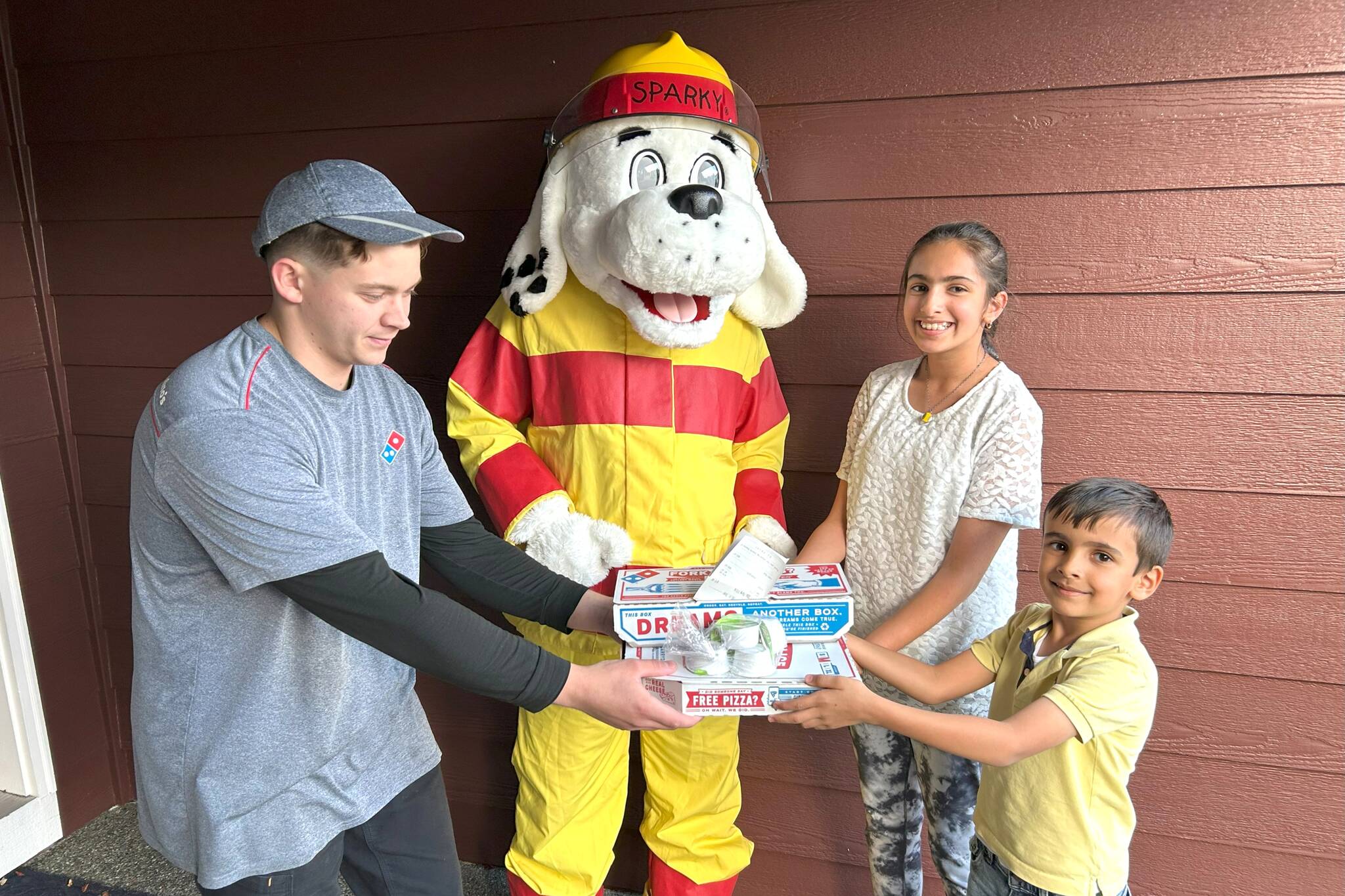 Sequim Gazette photo by Matthew Nash
Pizza fans Preet Saran, 10, and Jess Saran, 6, on right, receive free pizza from Domino’s delivery driver Ryan Lang and Sparky the Fire Dog on Oct. 8 as part of Fire Prevention Week efforts by Clallam County Fire District 3. Staff and volunteers, in partnership with Sequim Domino’s, checked homeowners’ smoke alarms and if they worked, they’d receive their orders for free.