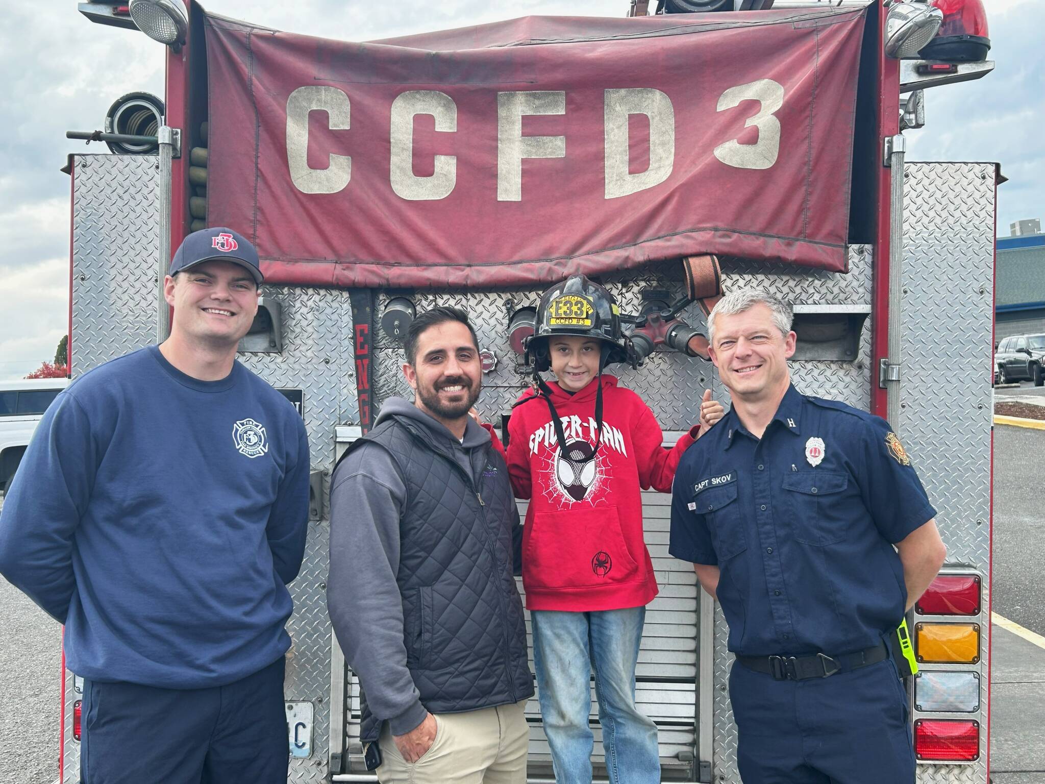 Sequim Gazette photo by Matthew Nash
Crisstepher MacRae Jr., third from left, is all smiles with dad Crisstepher MacRae Sr. and Clallam County Fire District 3 firefighters Jake Stanley, left, and Captain Kjel Skov, right, on Oct. 10. He was driven home after school in a fire engine for winning the Fire Escape Plan contest sponsored by the Sequim Gazette in partnership with Hi-Way 101 Diner and CCFD3.
