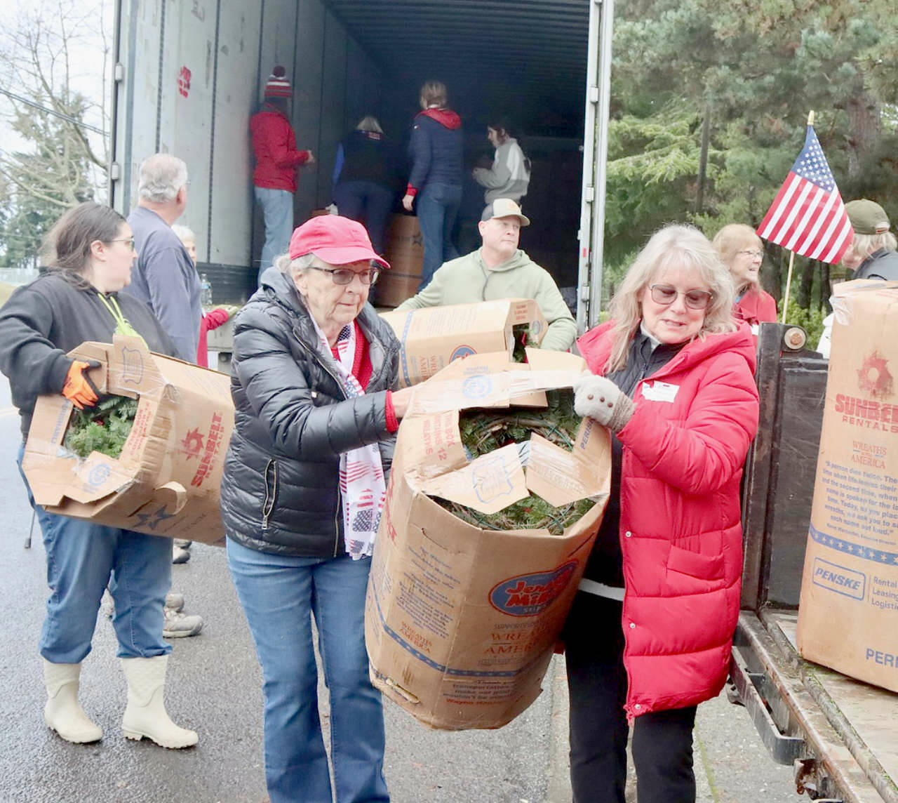 Olympic Peninsula News Group photo by Dave Logan/ Donna Bower, left, and Kristine Konopaski, volunteers from the Michael Trebert Chapter of the Daughters of the American Revolution, unload one of the 115 boxes of Christmas wreaths and carry it to a waiting truck.