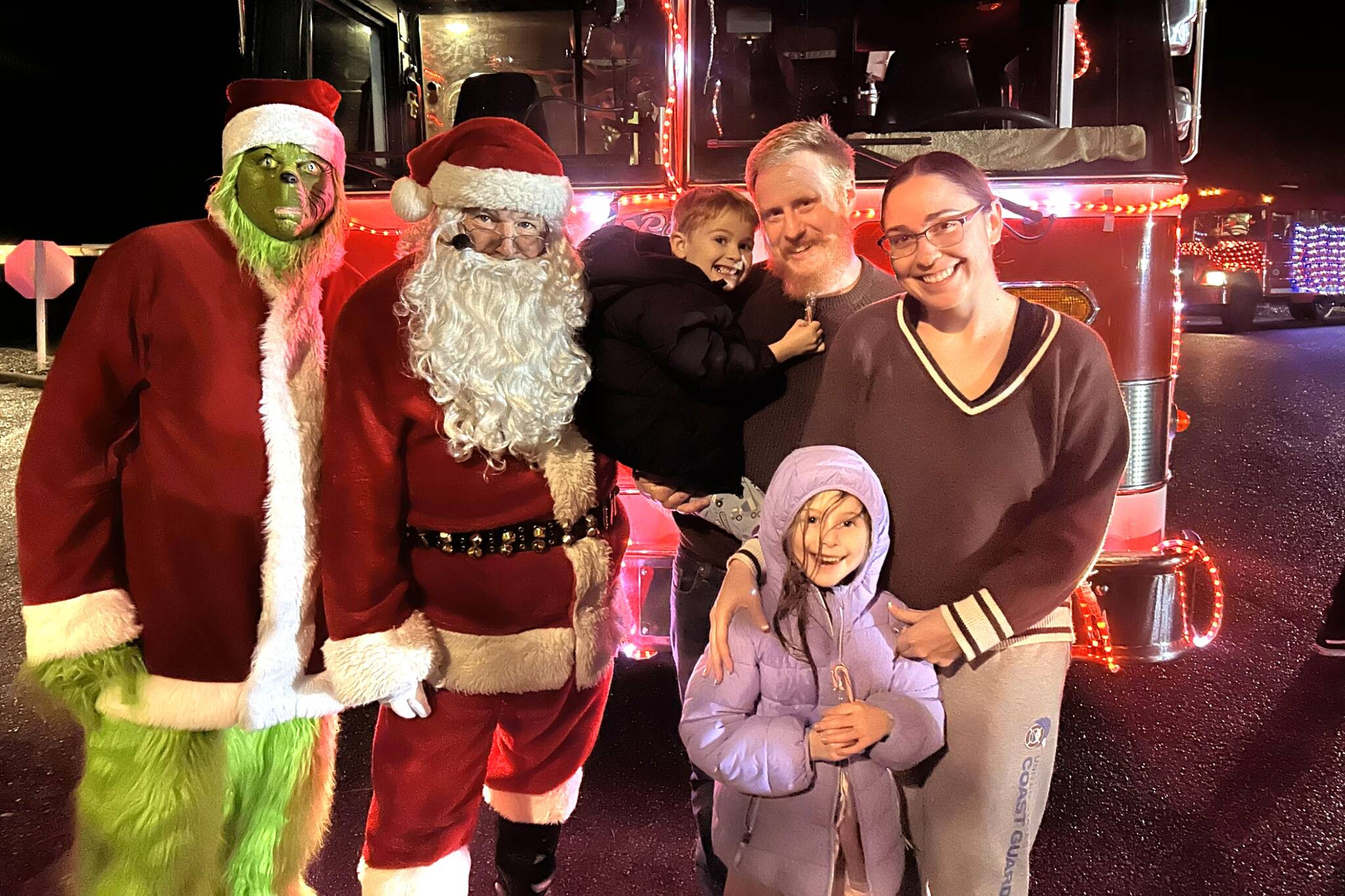 Sequim Gazette photo by Matthew Nash
The Grinch and Santa Claus take a photo with the Orr family - Jasper Orr, 5, dad TJ Orr, Charlie Orr, 8, and mom Lisa Orr - on Dec. 11 in Sunland during a stop for Santas Toy and Food Fire Brigade. Lisa Orr said they come out to visit Santa every year.