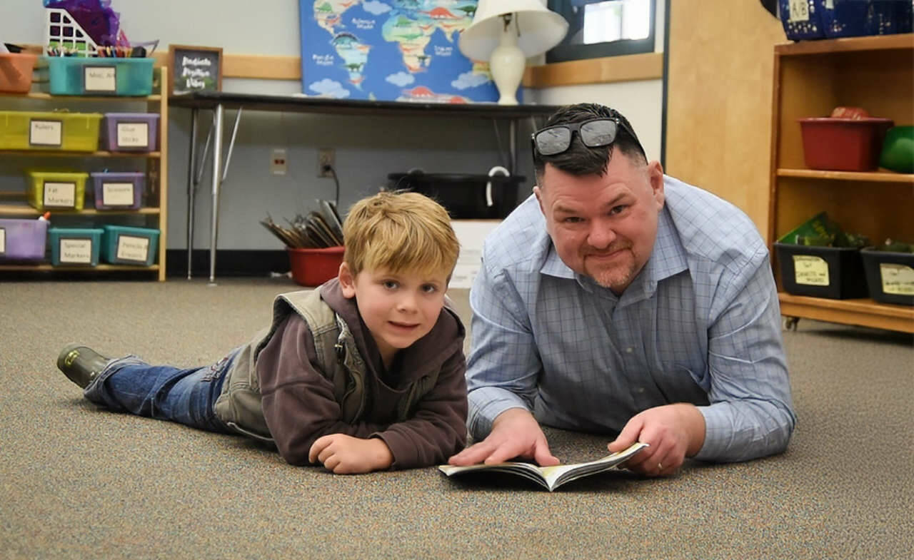 Sequim Gazette photo by Monica Berkseth/ Eric Pickens and kindergartener Carter Tyler enjoy some one-on-one storytime.