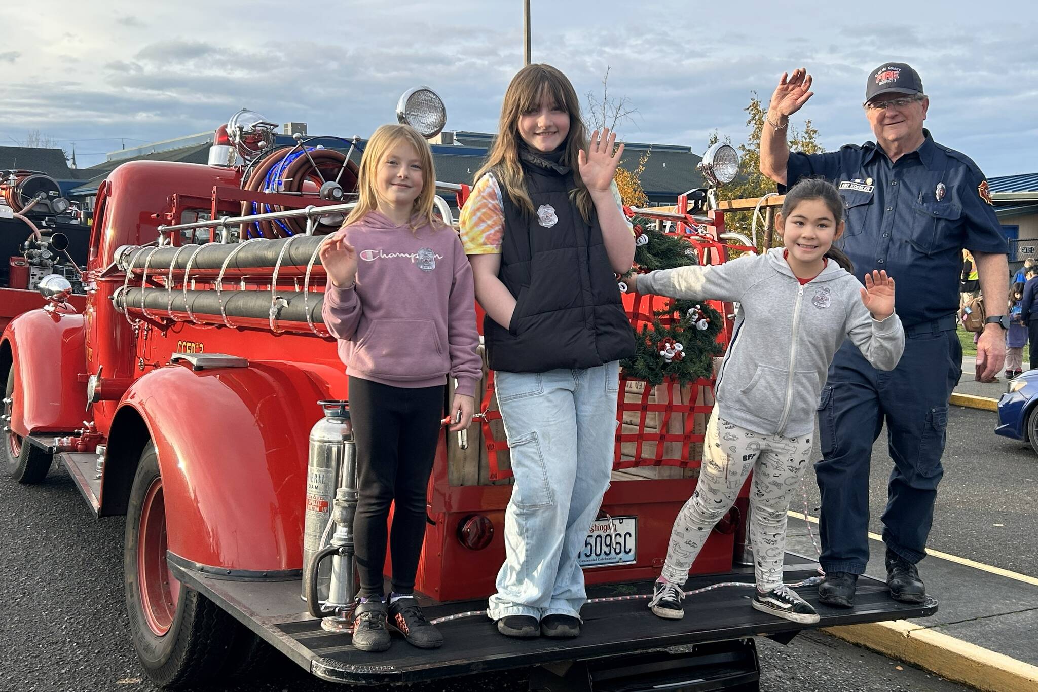 Sequim Gazette photo by Matthew Nash
Fourth graders, from left, Malta Bushy, Emma Stewart, and Sammy Nicholson stand with Keith Koehler, a volunteer EMS with Clallam County Fire District 3, prior to riding in a fire truck home from school at Helen Haller Elementary. Nicholson won the ride for receiving the most funds for Sequim Elementary PTAs Turkey Trot.