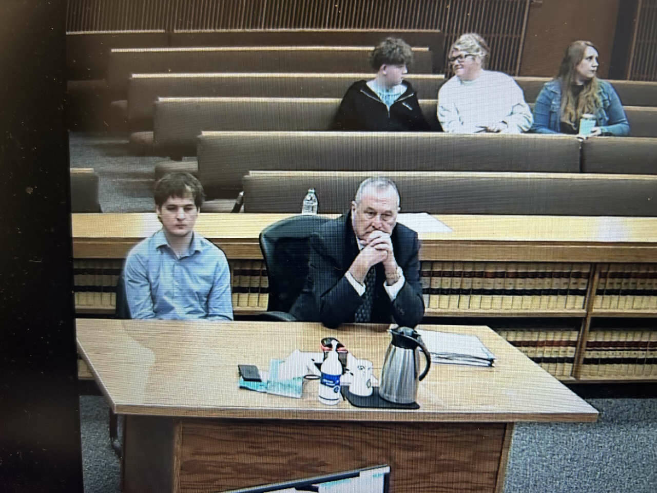 Clallam County Superior Court screenshot/
Cole Douglas, who was sentenced Thursday, Jan. 8 after pleading guilty to the March 2025 hit-and-run that seriously injured Sequim middle-schooler Colton Dufour, listens to Judge Elizabeth Stanley as Coltons mother, Cherie Tachell, seated several rows back, smiles at her son just minutes before Douglas was taken into custody to begin serving a 12-month jail sentence. Seated beside them is victims advocate Molly Ramsey, who works in the Clallam County prosecutors office and read a victims impact statement to the court during the almost 35-minute hearing.