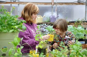 Sequim High School ninth-grader Caitlin Matson shows Haller second-grader Lily Hough around the Sequim High School greenhouse