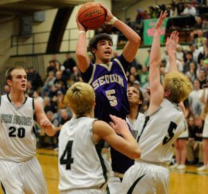 Sequim’s Payton Glasser looks to score as he shoots over Port Angeles defenders Grayson Peet (4)