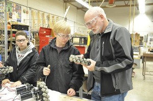 Volunteer and retired engineer Pat Volk mentors Sequim High School Robotics Club members Pearl Barry and Ryan Nestor after school in the wood shop.