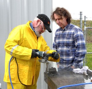 Machinist Bobby Kelly diamond polishes a high strength marine part as Allied Titanium CEO Christopher Greimes watches the process.