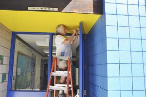 Therese Coleman paints doors at Helen Haller Elementary in the blue pod area.