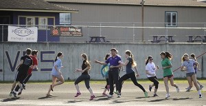 Sequim coach Brad Moore leads high jumpers in a warmup during a preseason practice last week.