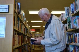 Bill Dickin of Sequim peruses the books in the Sequim Library where he serves as a volunteer. The North Olympic Library System
