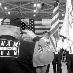 Mike Money of Port Angeles, a U.S. Navy veteran who served in Vietnam, salutes as a color guard passes during last Friday&rsquo;s Veterans Day ceremony in the hangar of U.S. Coast Guard Air Station/Sector Field Office Port Port Angeles. (Keith Thorpe/Peninsula Daily News)