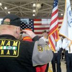 Mike Money of Port Angeles, a U.S. Navy veteran who served in Vietnam, salutes as a color guard passes during last Friday&rsquo;s Veterans Day ceremony in the hangar of U.S. Coast Guard Air Station/Sector Field Office Port Port Angeles. (Keith Thorpe/Peninsula Daily News)