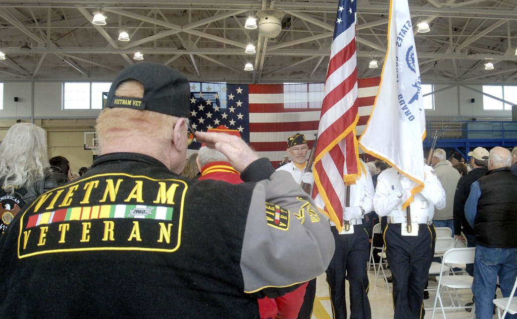 Mike Money of Port Angeles, a U.S. Navy veteran who served in Vietnam, salutes as a color guard passes during last Friday&rsquo;s Veterans Day ceremony in the hangar of U.S. Coast Guard Air Station/Sector Field Office Port Port Angeles. (Keith Thorpe/Peninsula Daily News)