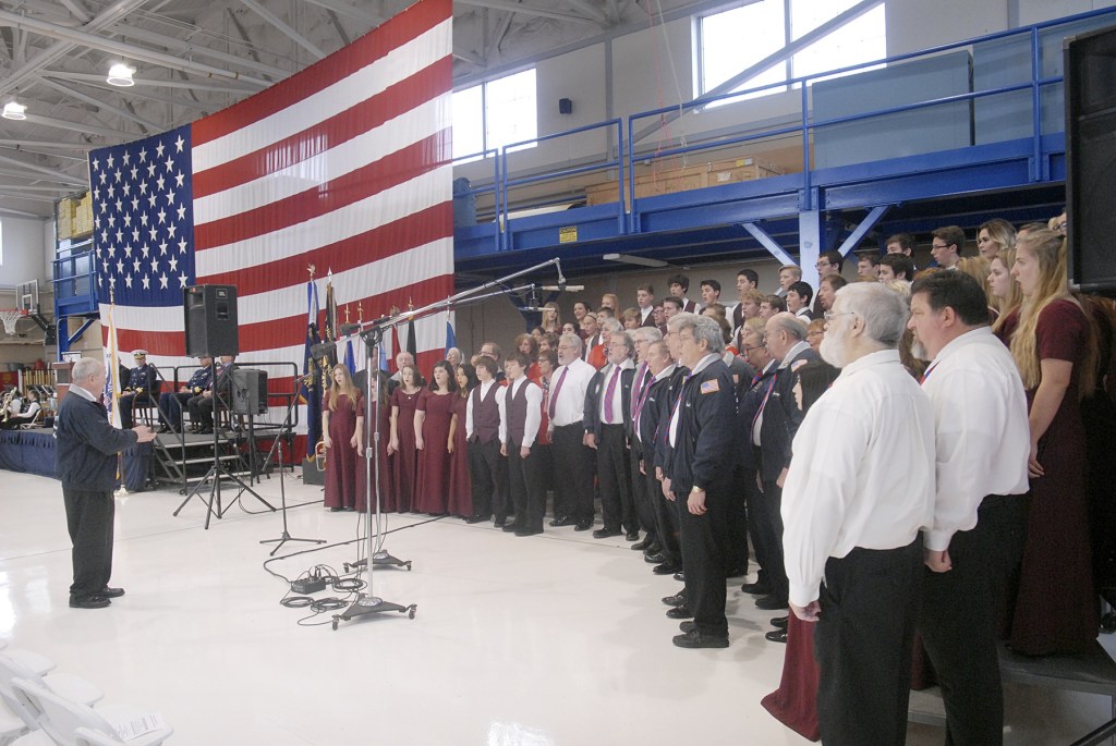 A combined chorus consisting of members of the Olympic Peninsula Men&rsquo;s Chorus, The Grand Olympics Chorus of Sweet Adeline&rsquo;s International, Mix Up A Capella and the Sequim High School Select Choir perform under the direction of Jim Davis during last Friday&rsquo;s Veterans Day ceremony in the hanger of U.S. Coast Guard Air Station/Sector Field Office Port Port Angeles. (Keith Thorpe/Peninsula Daily News)