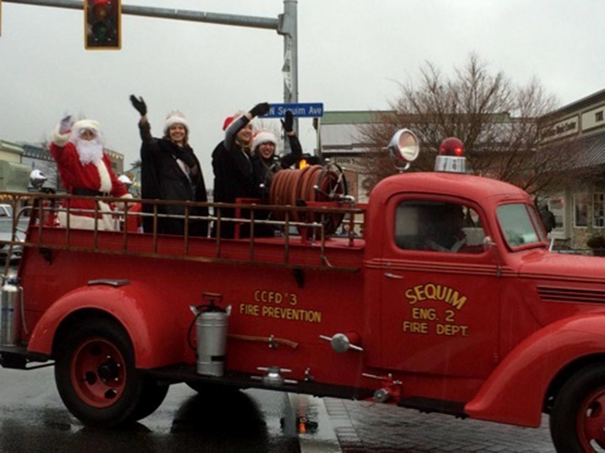 Above, Santa Claus and Sequim Irrigation Festival royalty ride on an antique fire truck from Clallam County Fire District 3. At right, members of the Sequim City Band warm up the crowd with lively music on Nov. 26 in Downtown Sequim. Submitted photos