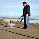 Scientist Robert Jeters, project manager for the Pacific Northwest National Laboratory&rsquo;s aggregator product, uses a propane burner to light an oil slick on fire during a recent demonstration. Sequim Gazette photo by Matthew Nash