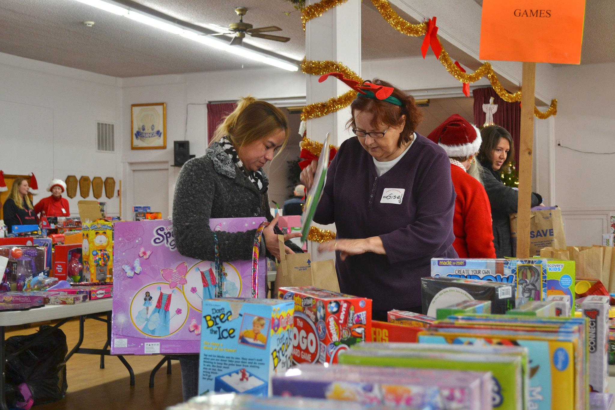 Farah Durham of Sequim looks for toys for her 4-year-old daughter with help from volunteer Gisele Gala at Toys for Sequim Kids on Dec. 14 in the Sequim Prairie Grange. &ldquo;It&rsquo;s a blessing to help others because God has blessed us so abundantly,&rdquo; Gala said. Sequim Gazette photo by Matthew Nash