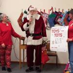 Sunbonnet Sue Quilt Club members Sharon Clayton and Marilyn Williams present Santa Claus with Clallam County Toys for Tots $1,208 in donations. Photo courtesy of Sharon Clayton
