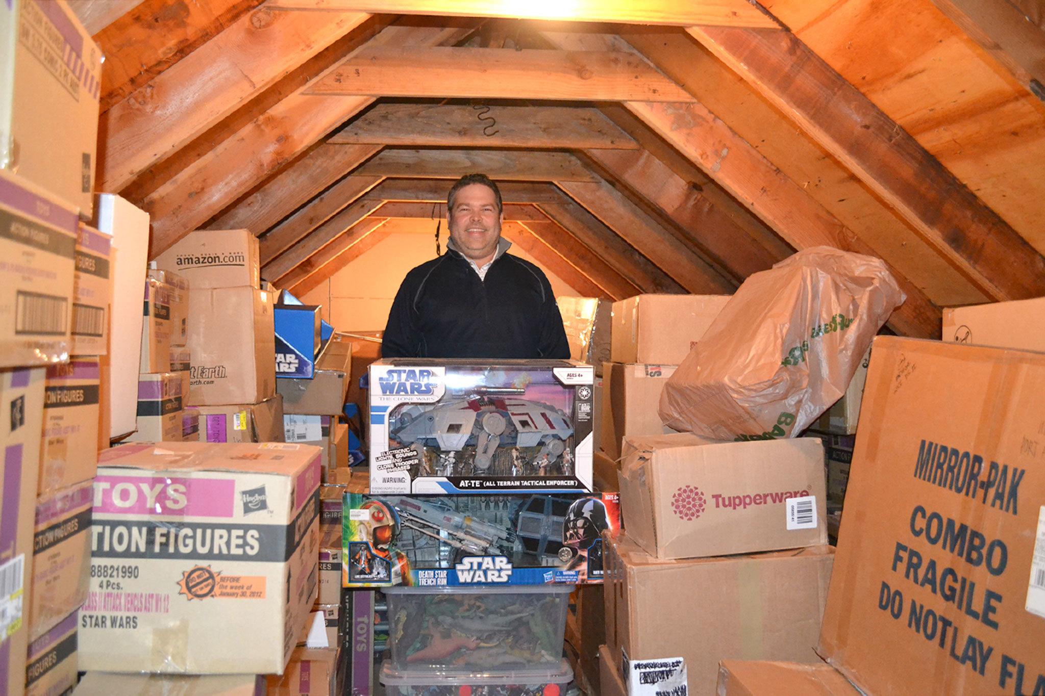 Jon Gray of Sequim stands in his attic with boxes of &ldquo;Star Wars&rdquo; toys he&rsquo;s collected since the mid-1990s. He buys two of each action figure with the goal to keep one in box and a second to display. Sequim Gazette photo by Matthew Nash