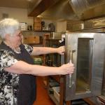 Laurie Campen, director of food services at the Sequim School District kitchen, opens an oven from the 1970s with only one door that opens. Sequim Gazette photo by Erin Hawkins