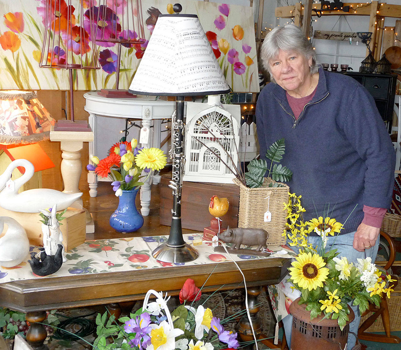 J. Brzoska, owner of The Rusting Rooster, knows a &ldquo;cool find&rdquo; when she sees one. She displays one of her favorites, a clarinet she repurposed into a table lamp. Sequim Gazette photo by Patricia Morrison Coate