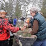 Vince Penn of the Quileute Tribe, left, and Frank Hanson, education and outreach coordinator at the University of Washington&rsquo;s Olympic Natural Resources Center, shake hands as a hand-made canoe carved by William E. Penn is removed from Pioneer Memorial Park on April 8. Sequim Gazette photo by Michael Dashiell