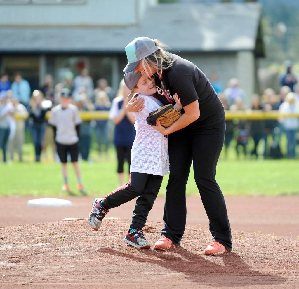 Above, Naomi Perry gives son Kingston a big hug after throwing out one of two opening day ceremonial first pitches. Sequim Little League paid tribute to Perry&rsquo;s father Dan, a longtime local youth sports advocate, on April 15.                                 At left, brothers Trevor Goff, 8, (background) and Connor Goff, 9, have a game of catch after opening Sequim Little League Opening Day ceremonies.