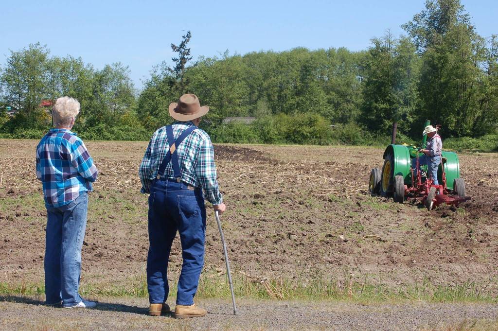 Chris Baker, left, stands with Dick Bekkevar as Dave Bekkevar plows a field at the Pumpkin Patch in Sequim for the annual Plow Day on Saturday, May 20. Sequim Gazette photo by Erin Hawkins