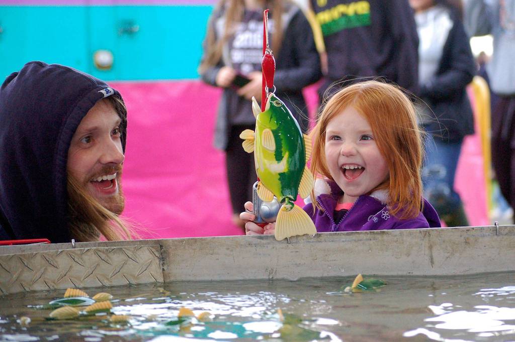 Three-year-old Annabel Lee of Bremerton celebrates a catch in the fish pond with her dad Alexender Lee at the Sequim Irrigation Festival&rsquo;s carnival on Saturday. Sequim Gazette photo by Matthew Nash