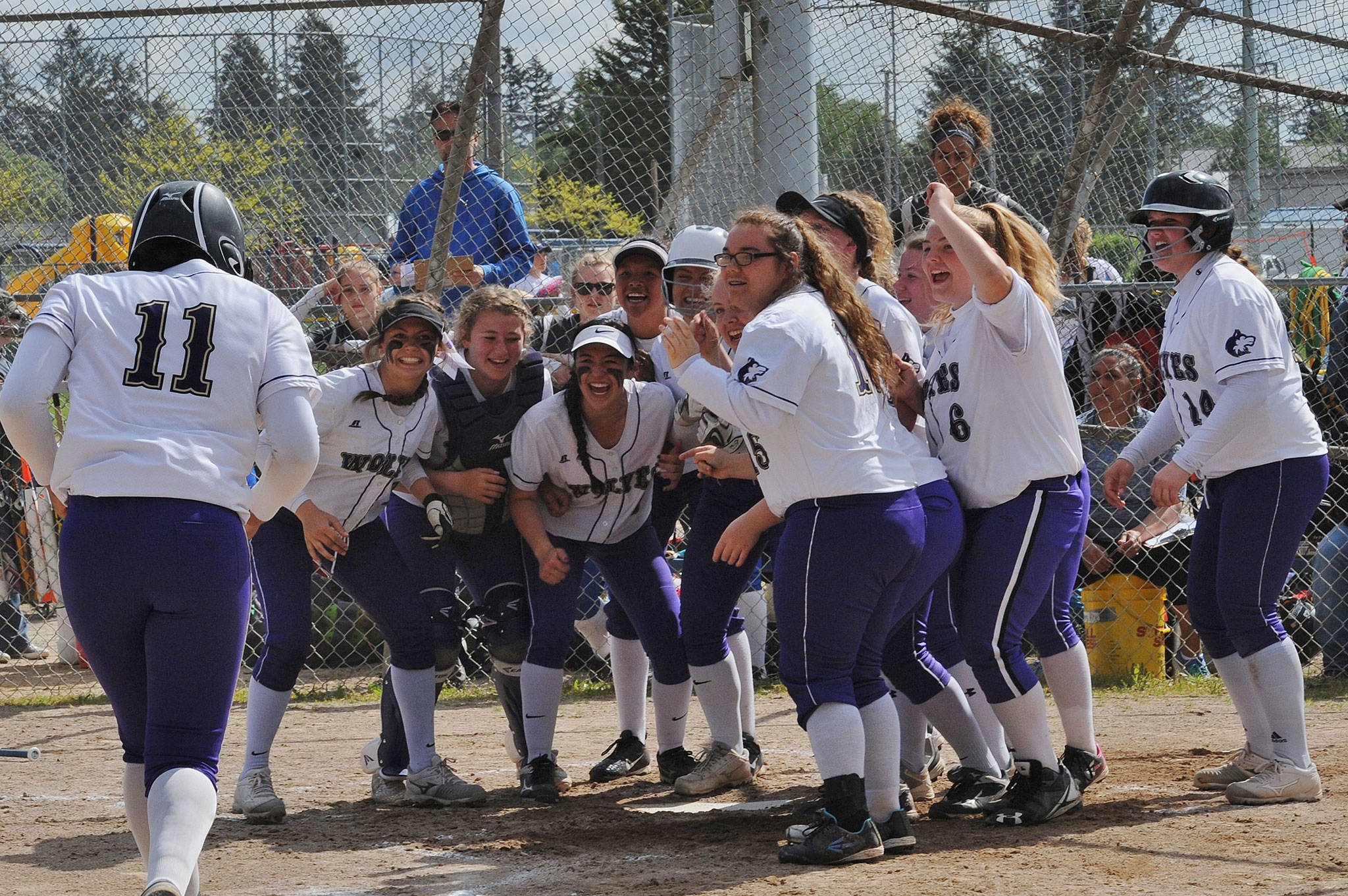 Adrianne Haggerty is greeted at home plate by a pack of happy Wolves after her home run against Olympic on Saturday during Sequim&rsquo;s 9-1 win. Photos by Lonnie Archibald