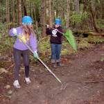 Sequim High freshmen Kjirstin Foresman, left, and Mazie Whitteker, use rakes to clear debris from a new trail they and other high schoolers worked to build on Miller Peninsula from May 2-4. They learned about sharing the trail with bicyclists and stock, careers in forestry management and about different tools for clearing trails. Sequim Gazette photo by Matthew Nash