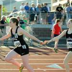 Sequim&rsquo;s Rylee Gray, left, gets a handoff from teammate Daisy Ryan in the anchor leg of the 4x400 relay on May 25. Sequim Gazette photos by Michael Dashiell