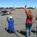 Ricki McLaughlin of Port Angeles, center, waves at the arrival of a vintage TF-51D Mustang as Kelly Thomas of Sequim, left, and Jenna McGoff, 13, of Port Angeles take photos. (Keith Thorpe/Peninsula Daily News)