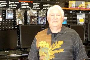 Jim Manderscheid, co-owner of Quality Assured Computer Services, displays a wall full of affordable refurbished computers. Sequim Gazette photo by Patricia Morrison Coate