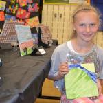 Brooklyn Fatherson, 8, of Renee Mullikin&rsquo;s art class, holds her tile art at the Helen Haller art show on June 12.
