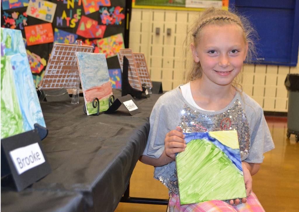 Brooklyn Fatherson, 8, of Renee Mullikin&rsquo;s art class, holds her tile art at the Helen Haller art show on June 12.