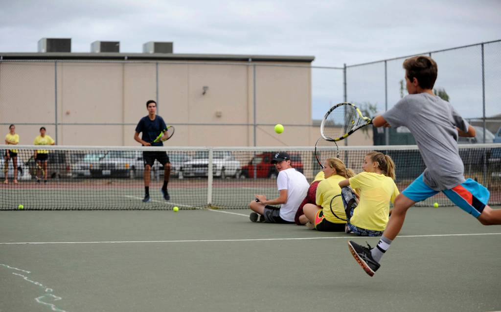 Blake Wiker (background) awaits a return volley in a game with experienced Tennis Academy campers. Sequim Gazette photo by Michael Dashiell